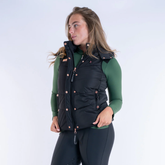 Woman wearing a black puffer gilet over a green base layer on a white background